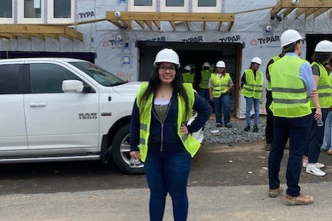 Female student with hardhat in front of construction site