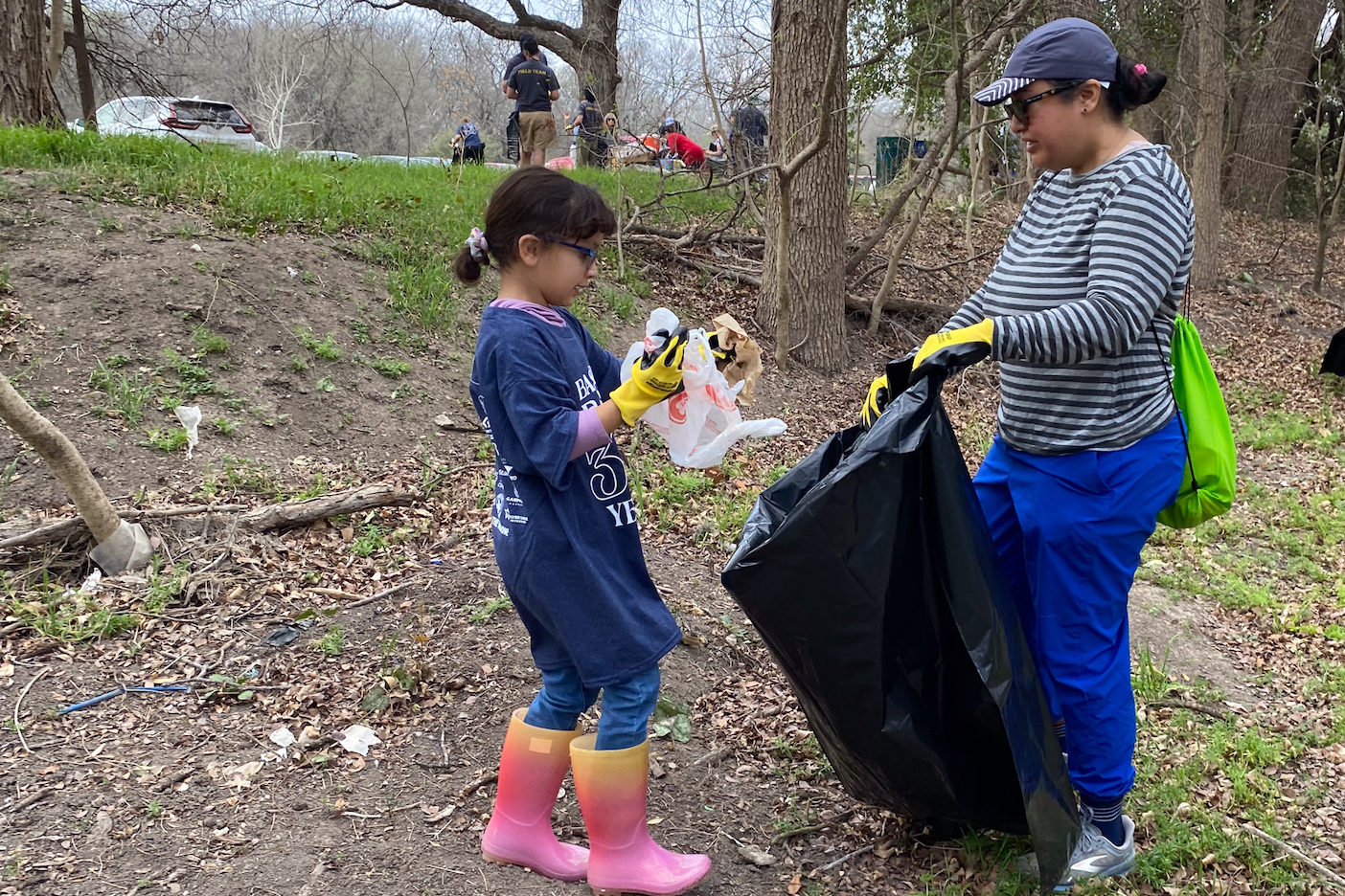 student and parent pick up trash from creek