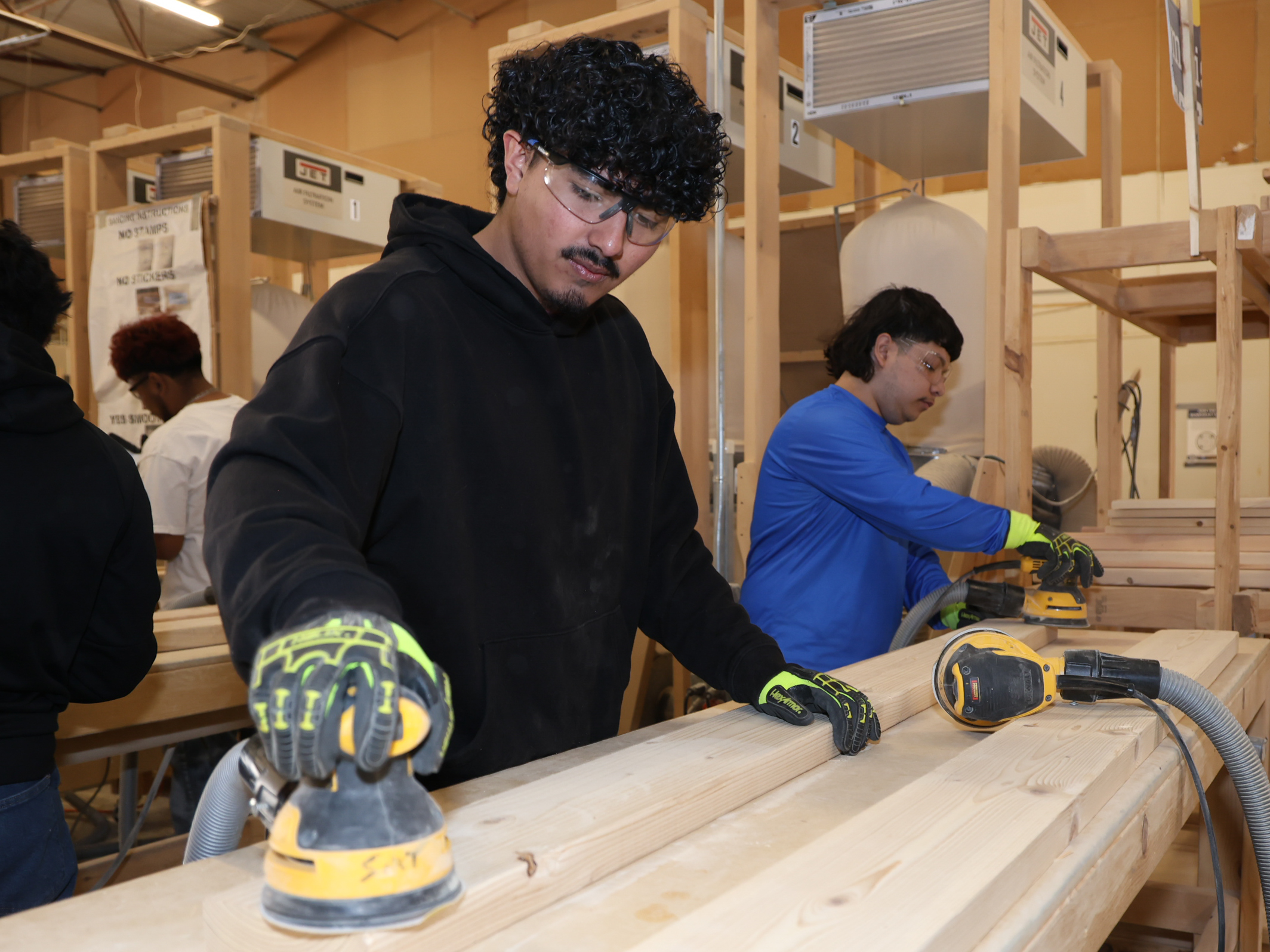 male student with safety goggles sands board
