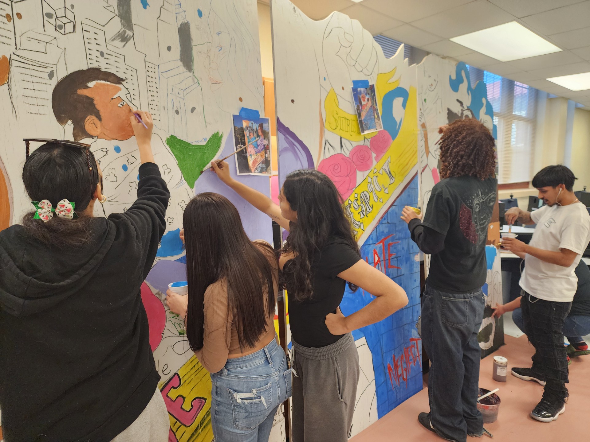 students paint inside outlined mural