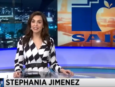 News anchor in front of a screen of the SAISD log