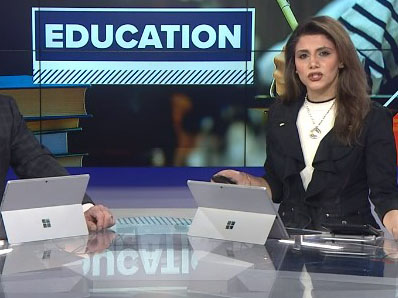 News anchor in from of a screen that says education