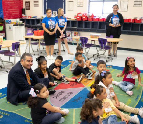 Superintendent Jaime Aquino sitting on the floor with children