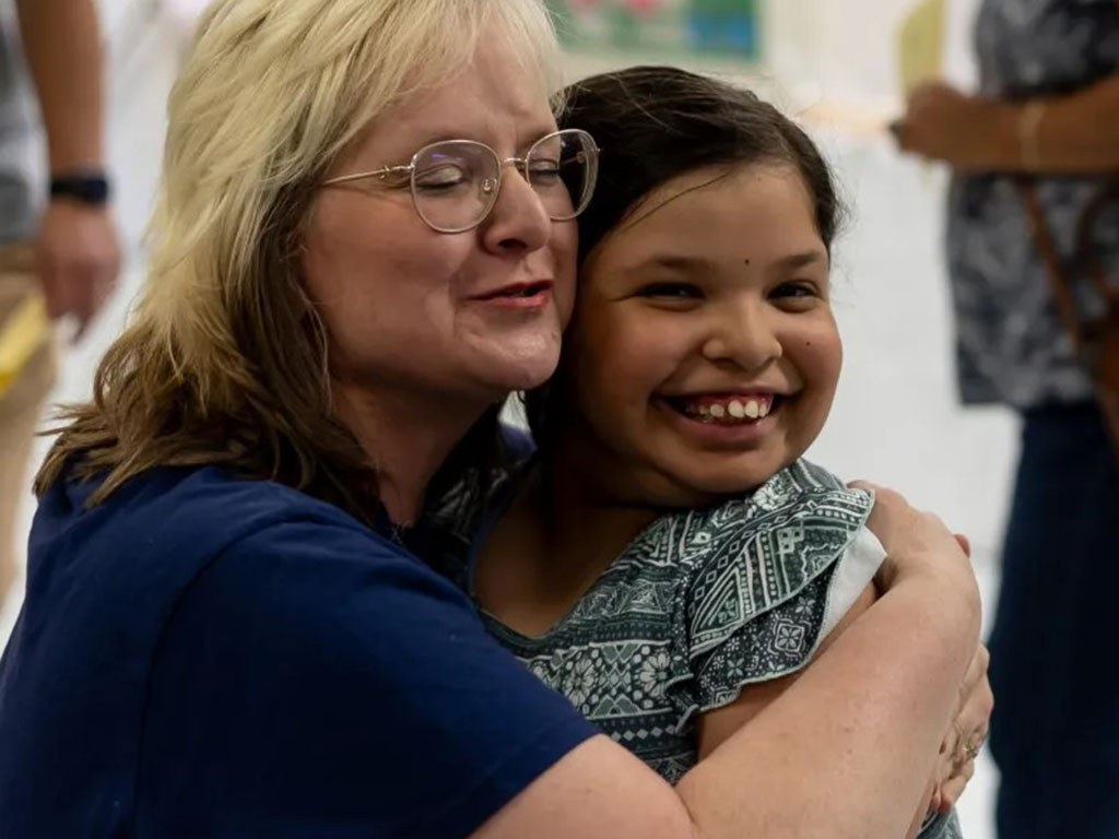 A teacher hugs a student