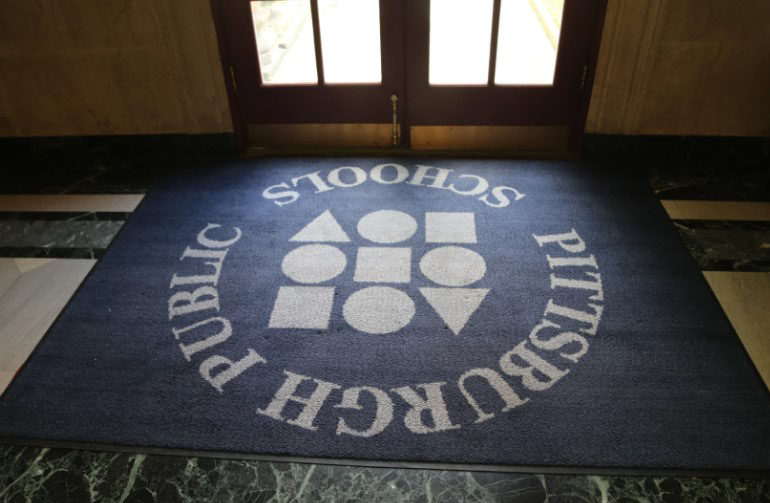 Pittsburgh Public Schools logo on a carpet in front of a door